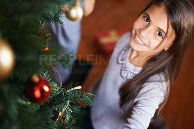 Buy stock photo Portrait, child and smile by Christmas tree in home, festive season and happy to prepare for xmas. Female person, girl and care for decoration on religious holiday, celebration and love for tradition