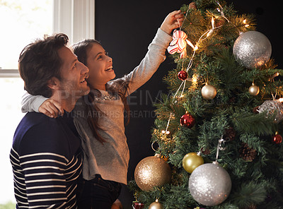 Buy stock photo Shot of a young girl and her father decorating the Christmas tree together