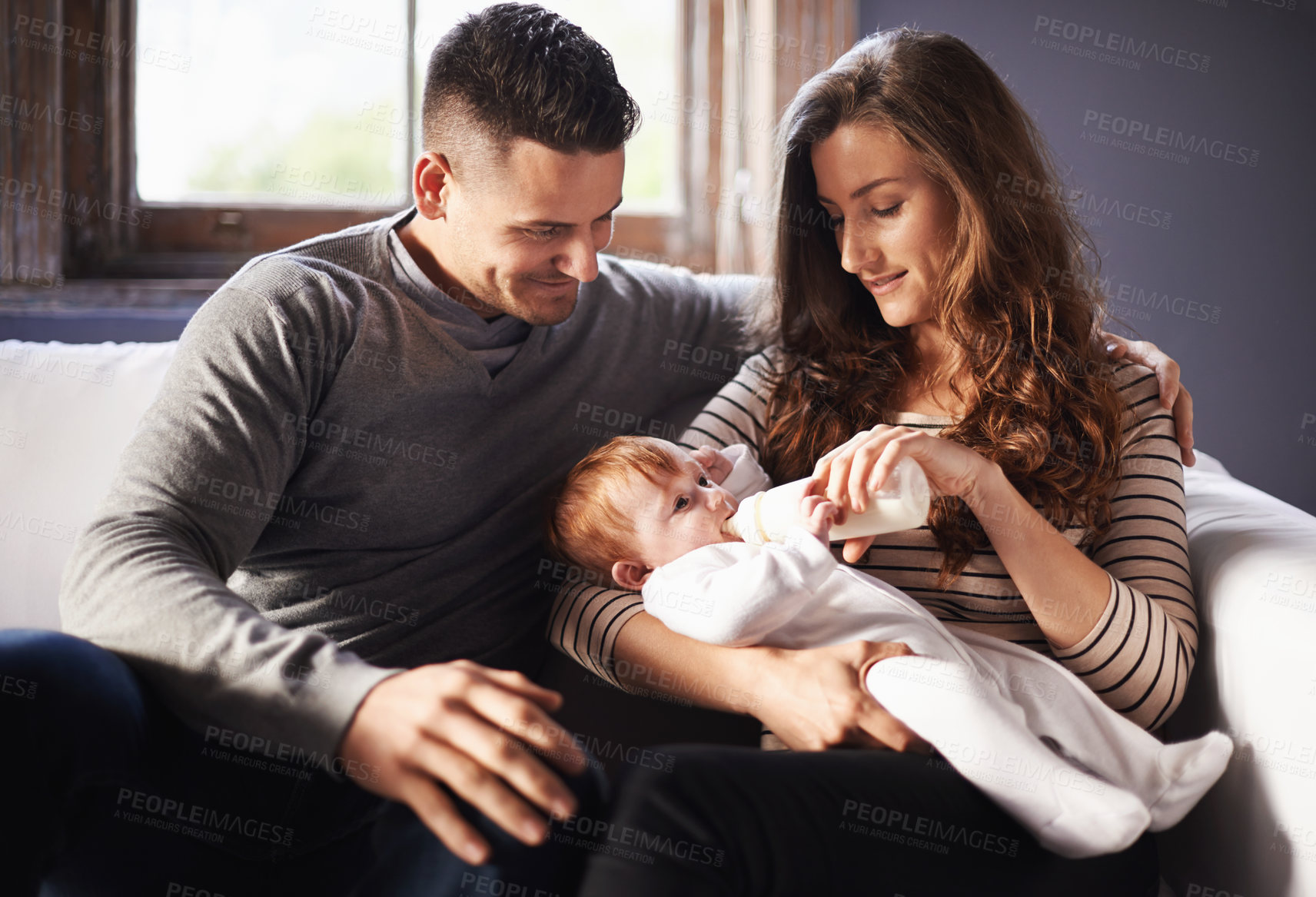 Buy stock photo Mother, baby and milk feeding with dad in a family home with love, support and care together. Smile, relax and bottle for youth development and growth with mom and father on a living room sofa