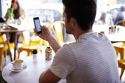 Buy stock photo Shot of a man using his mobile phone while sitting at a restaurant table
