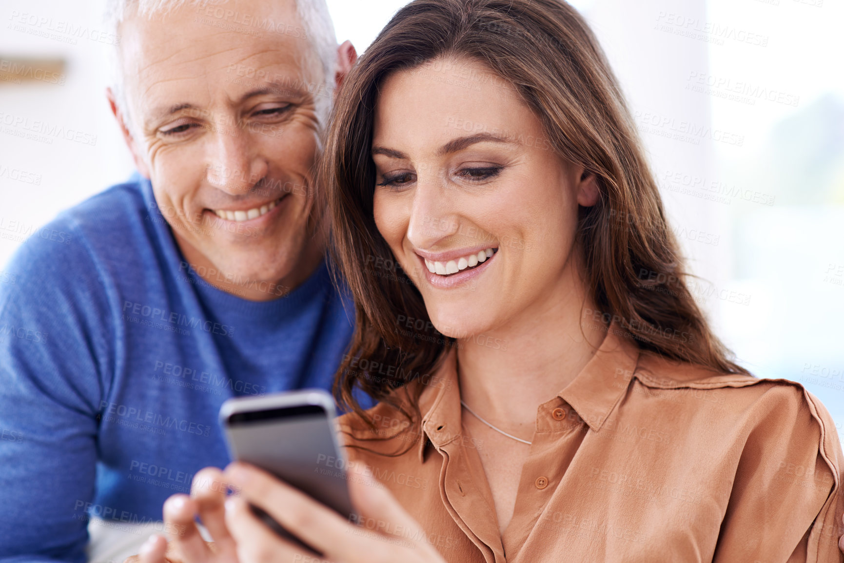 Buy stock photo Couple, phone and smile in home to relax with reading, search and mobile app for contact with bonding. People, woman and mature man on smartphone for notification, typing and web connection in house