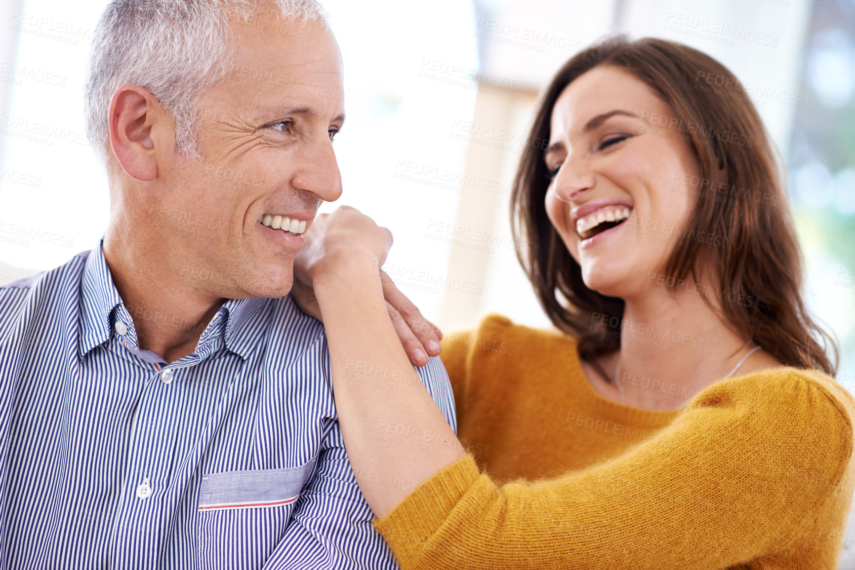 Buy stock photo Couple, happy and laughing in home for hug with support, funny joke and romance in living room of house. Senior man, woman and comic with face for embrace, trust and healthy relationship in apartment