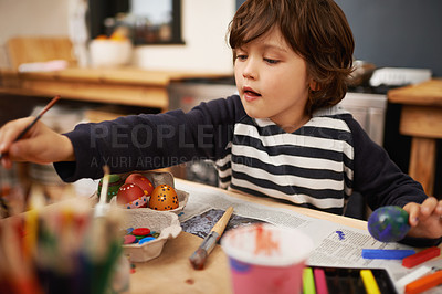 Buy stock photo Happy child, creative and color painting of eggs and celebration of easter holiday in home. Young, artist and boy with inspiration for learning craft, mural and paintbrush with supplies in kitchen