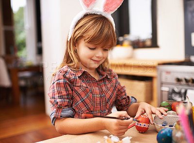 Buy stock photo Shot of a smiling little girl painting an easter egg at home