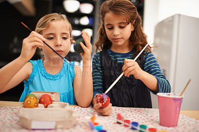 Buy stock photo Shot of two little girls painting easter eggs