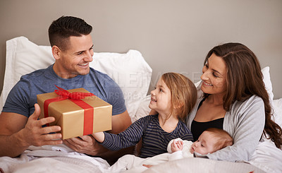 Buy stock photo Shot of a happy family giving their father a gift in bed