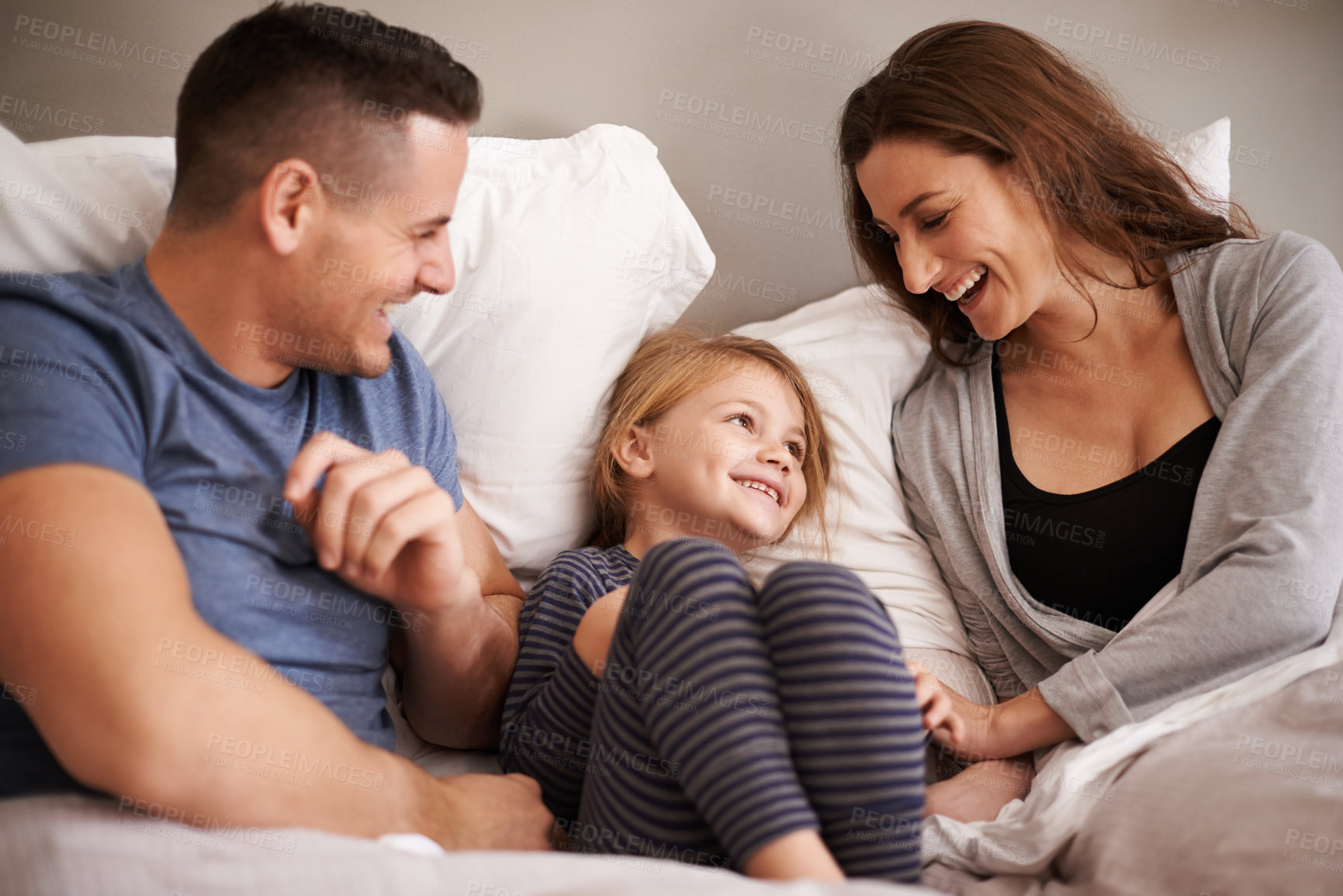 Buy stock photo Cropped shot of an affectionate young family lying in bed together