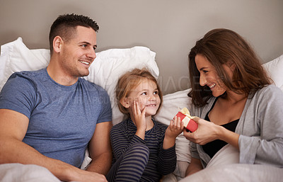 Buy stock photo Shot of a little girl receiving presents in bed from her parents