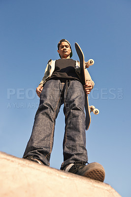 Buy stock photo Skatepark, serious and portrait of man with skateboard practicing for competition with skills. Fitness, hobby and bottom view of young male skater on ramp for outdoor training with blue sky.