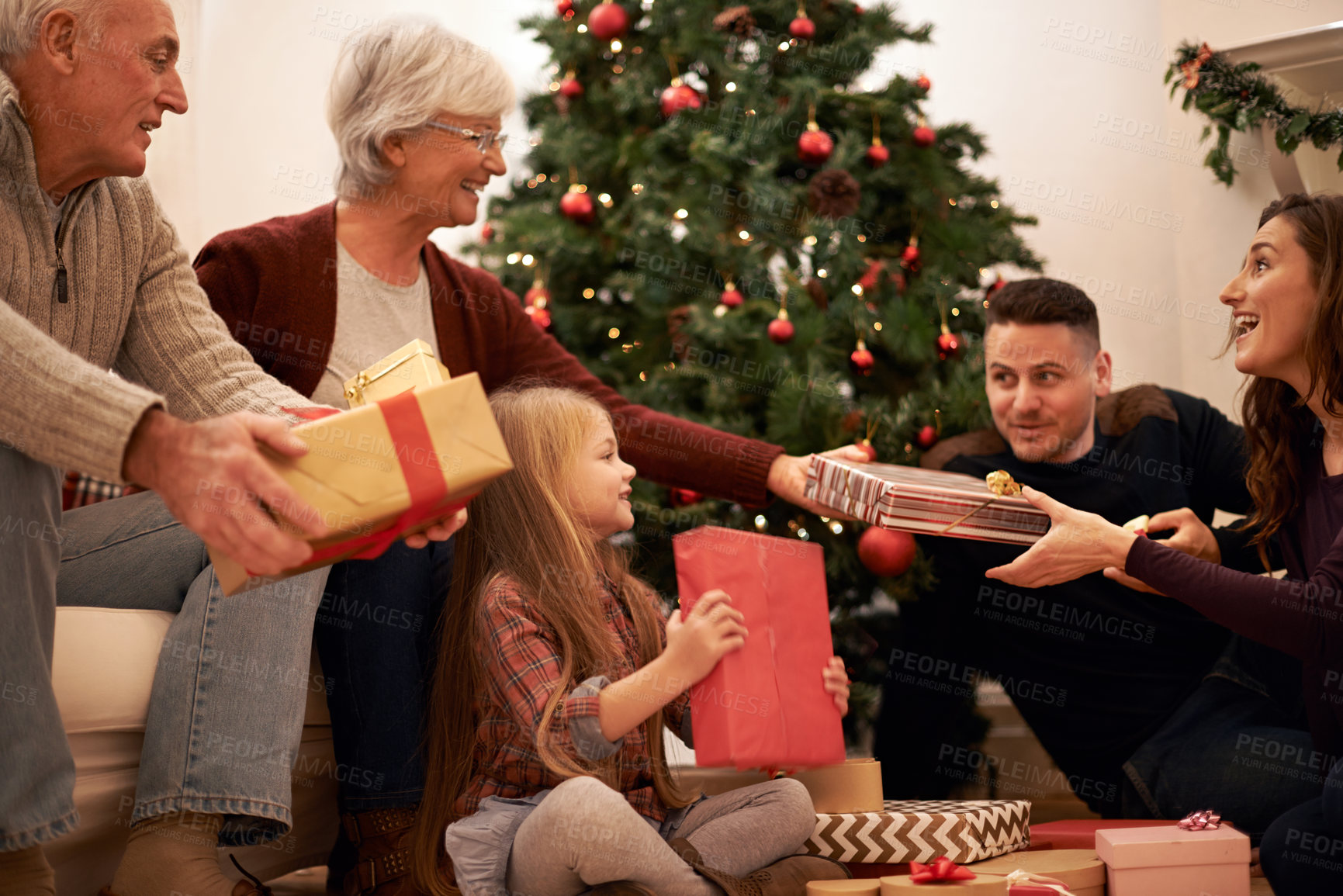 Buy stock photo Family, present and christmas in home with love, giving and care together at holiday event. Happy, smile and tree with celebration, child and marriage in a house with grandparents and festive gift