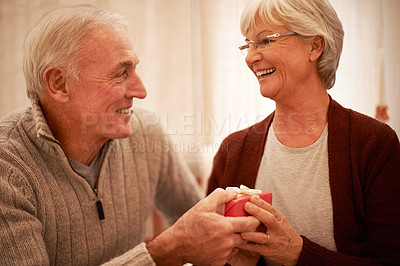 Buy stock photo Senior couple, love and gift in house or home living room for valentines day, marriage anniversary or birthday celebration. Smile, happy or retirement elderly man and woman bonding with present box