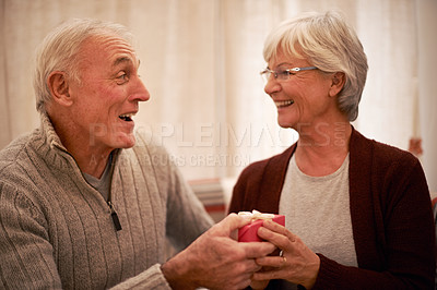 Buy stock photo Elderly, couple and giving gift for Christmas, holiday celebration and happy together with love and care. Smile, wow and celebrate, man giving woman present at home with festive season and holidays.