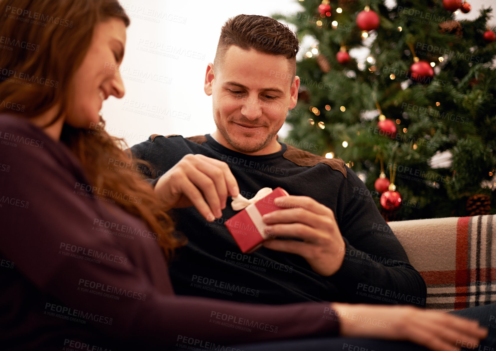 Buy stock photo Christmas, present and couple on a sofa for gift exchange, bond and relax while celebrating in a living room. Box, present and love by man and woman on a couch for festive, xmas and traditional day