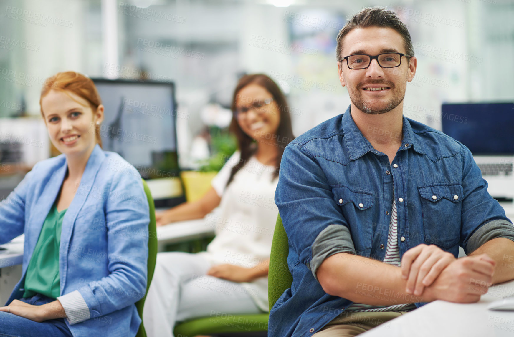 Buy stock photo Shot of three smiling colleagues working at the office