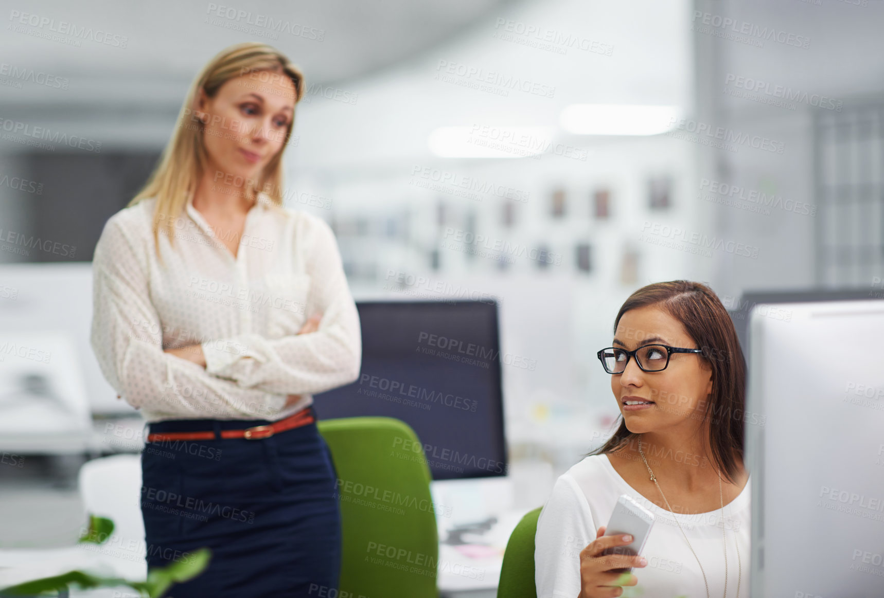 Buy stock photo Shot of an attractive female looking pensive being watched by her boss in an office setting