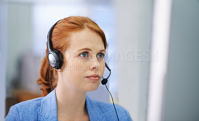 Buy stock photo Shot of an attractive red headed female serious about an enquiry she has on her headset