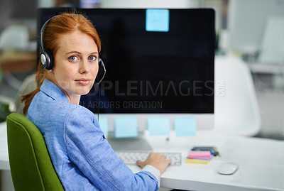 Buy stock photo Shot of an attractive red headed woman looking over her shoulder in headsets at work