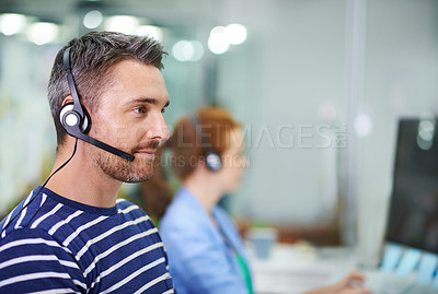Buy stock photo Shot of a young businessman wearing a headset in an office setting