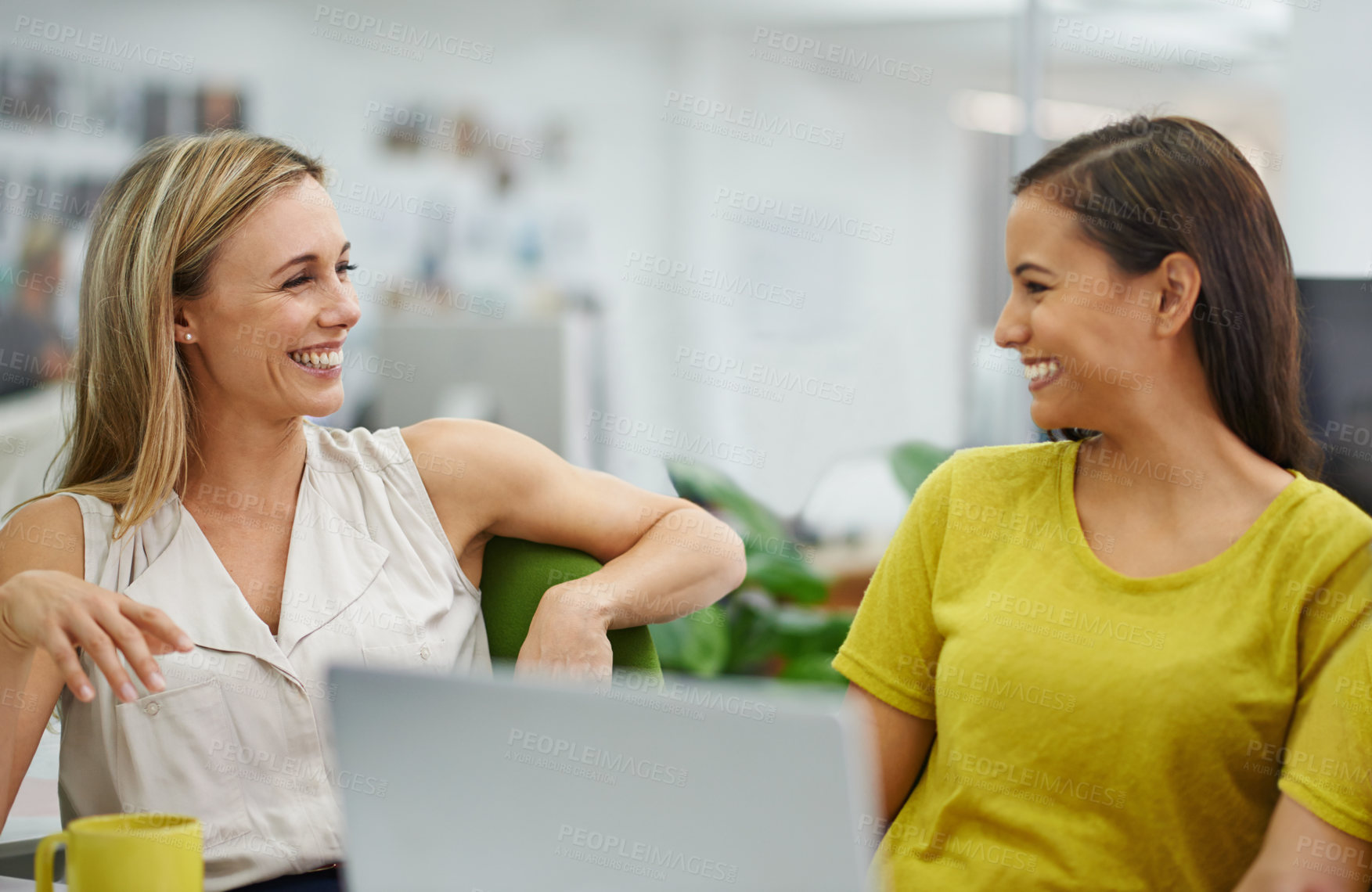 Buy stock photo Two attractive females laughing at their desk in the office