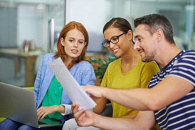 Buy stock photo Three co-workers looking over some work documents in the office