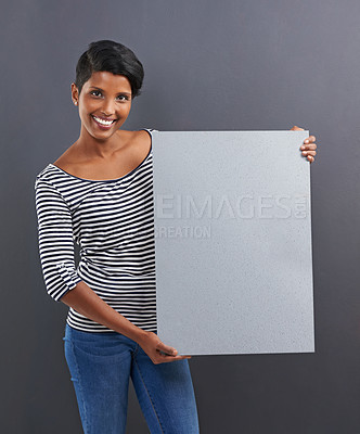 Buy stock photo Happy woman, portrait and presentation with poster for advertising or marketing on a gray studio background. Young female person or Indian with smile, billboard or notification sign on mockup space
