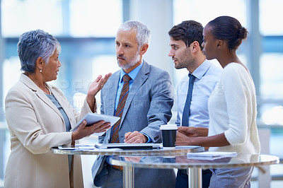 Buy stock photo A mature businesswoman with a tablet explaining something to her colleagues in a meeting
