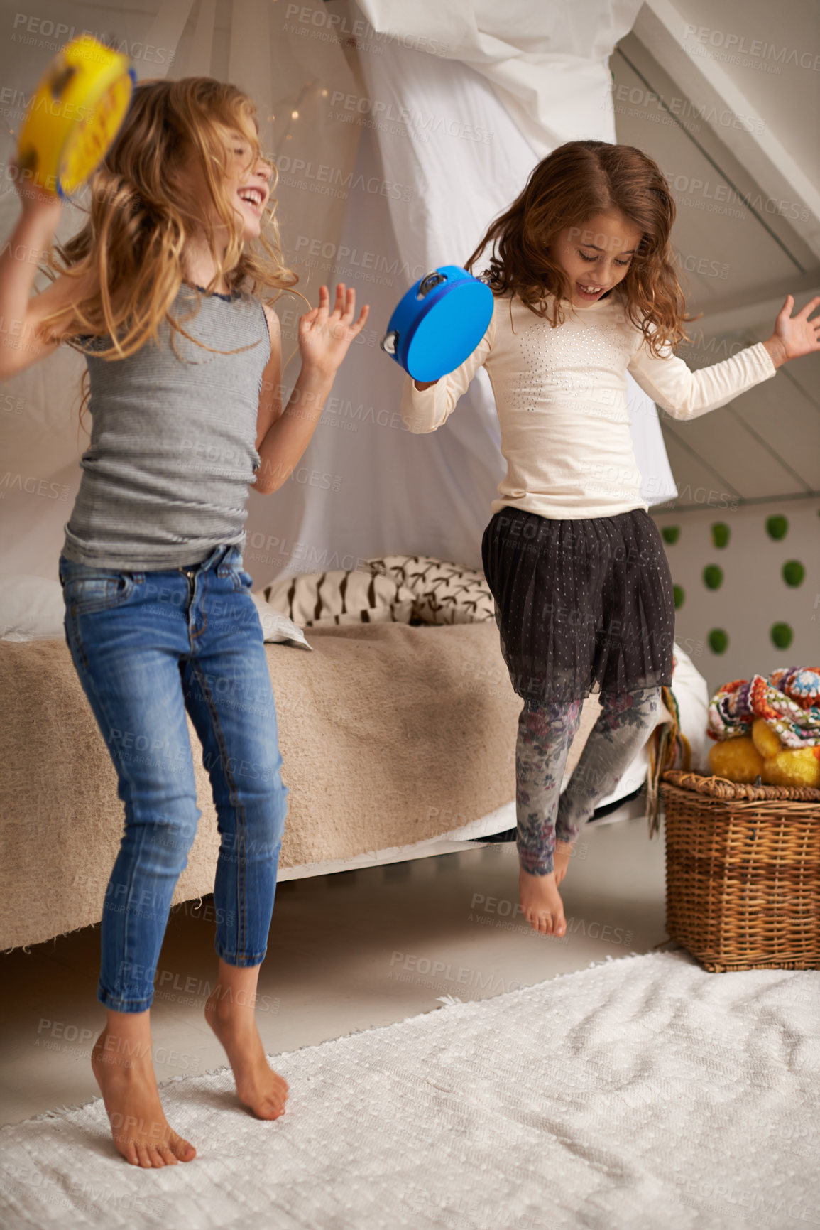 Buy stock photo Shot of two cute little girls playing with tambourines at home