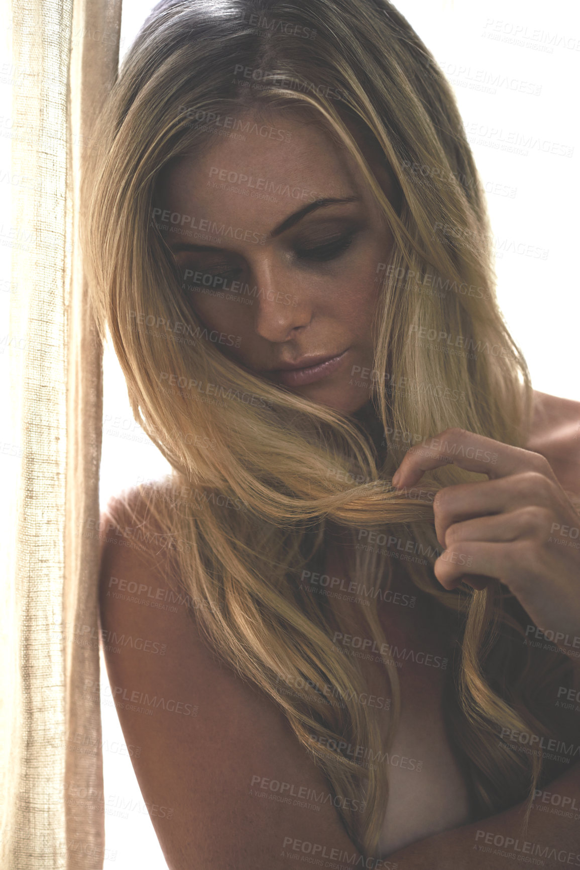 Buy stock photo Shot of a sultry young woman playing with her hair