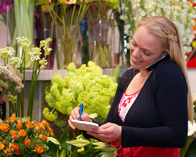 Buy stock photo Small business, woman on phone call and in florist writing an order. Flowers or plants, communication or customer service and female worker with smartphone or cellphone with client for a bouquet