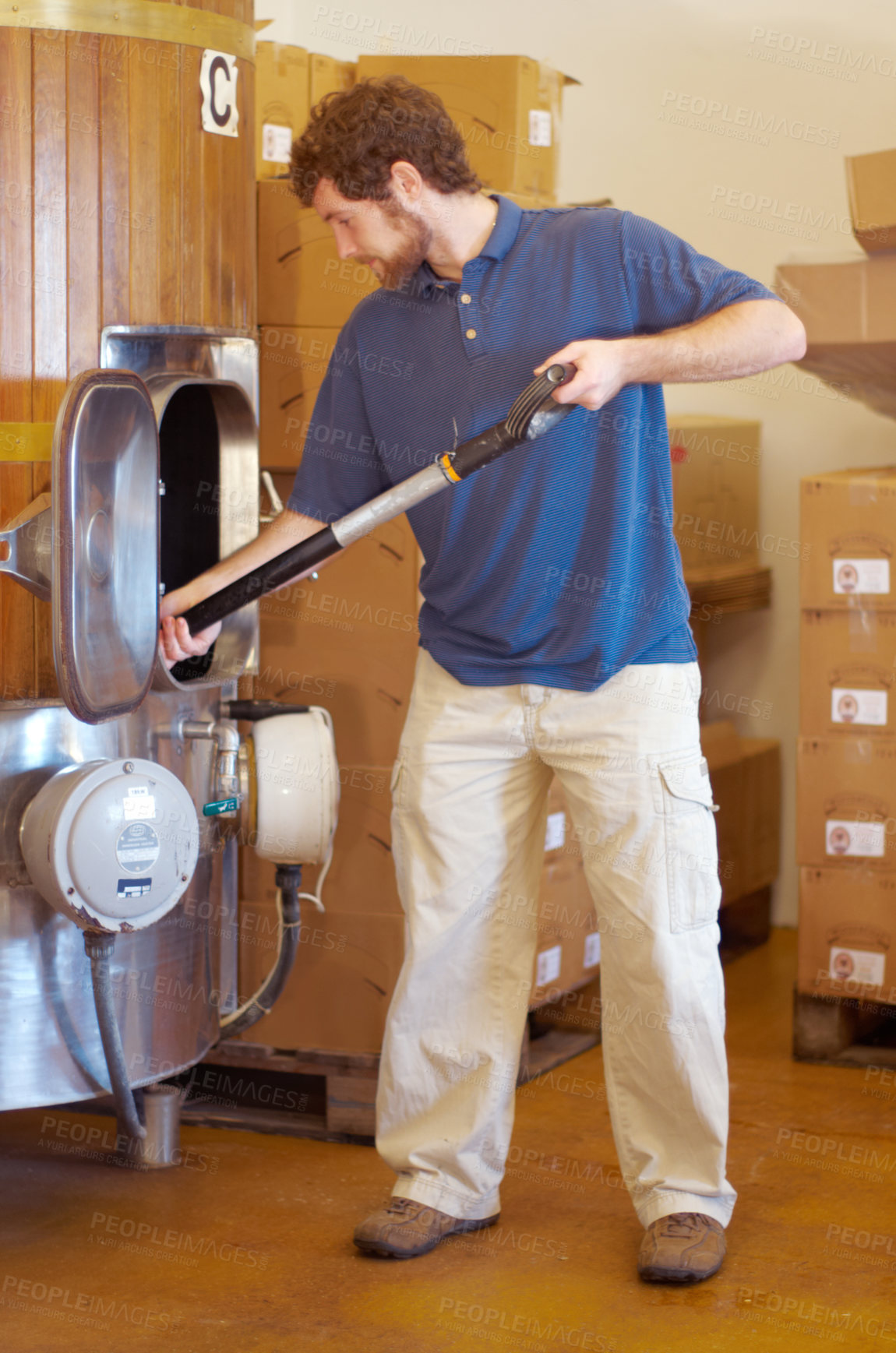 Buy stock photo Beer, distillery and person manufacturing alcohol drink in the brewery industry or working on the fermentation process. Product, labour and young man making a craft in a storage or warehouse