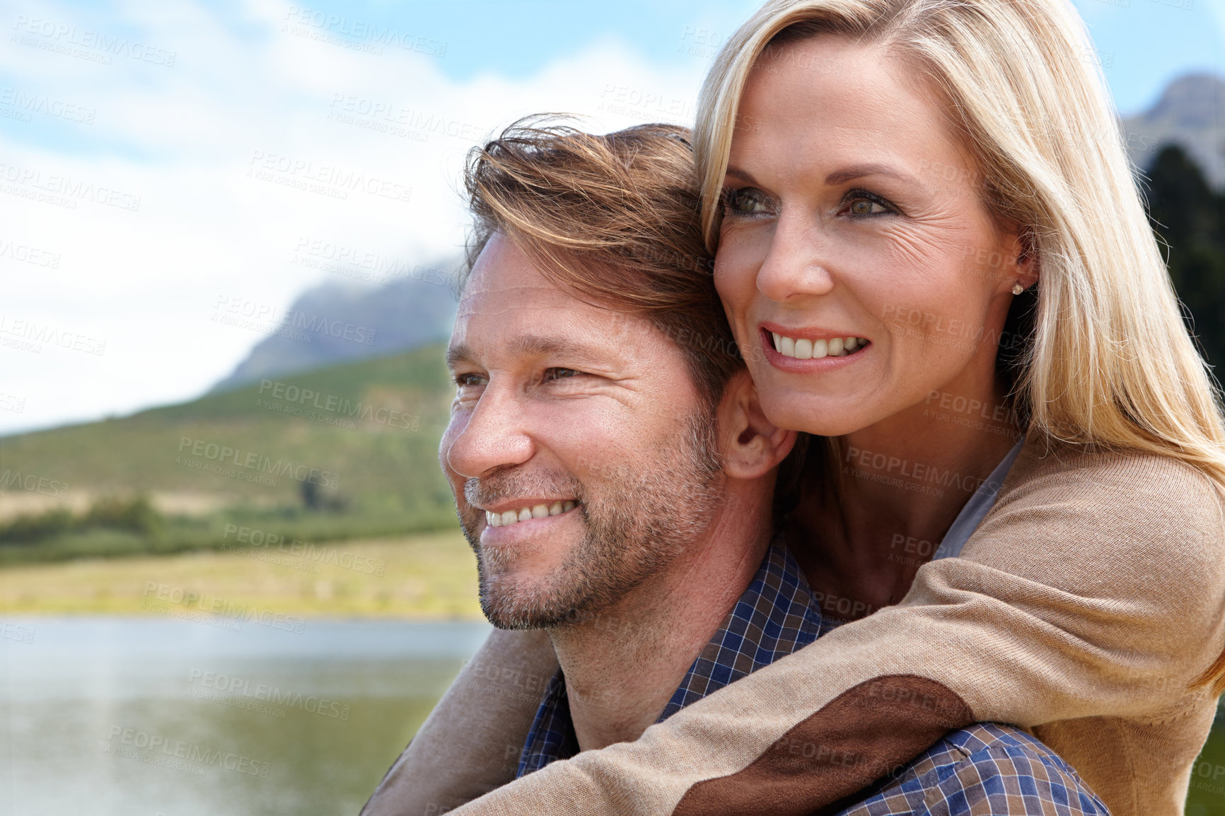 Buy stock photo Shot of a loving mature couple sitting beside a lake in the countryside