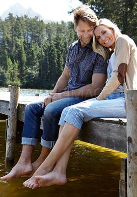 Buy stock photo Couple, lake and sitting on pier, portrait and happy with care on vacation, relax or memory in summer. Man, woman and river with smile, care or bonding with connection for love on holiday in Colorado