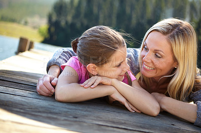 Buy stock photo Mother, daughter and relax on pier by a lake, bonding in nature or camping with holiday, travel and family time. Love, support and trust, woman and young girl outdoor for adventure and fresh air
