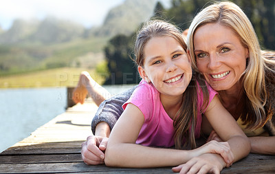 Buy stock photo Mom, daughter and relax on pier by a lake, bonding in nature or camping with holiday, travel and family time. Love, support and trust, woman and young girl outdoor for adventure and fresh air