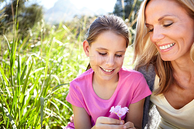 Buy stock photo Smile, girl and mother with flower in nature for childhood development, bonding and relax in field together. Woman, happy and child with plant for vacation, summer holiday or adventure by green grass