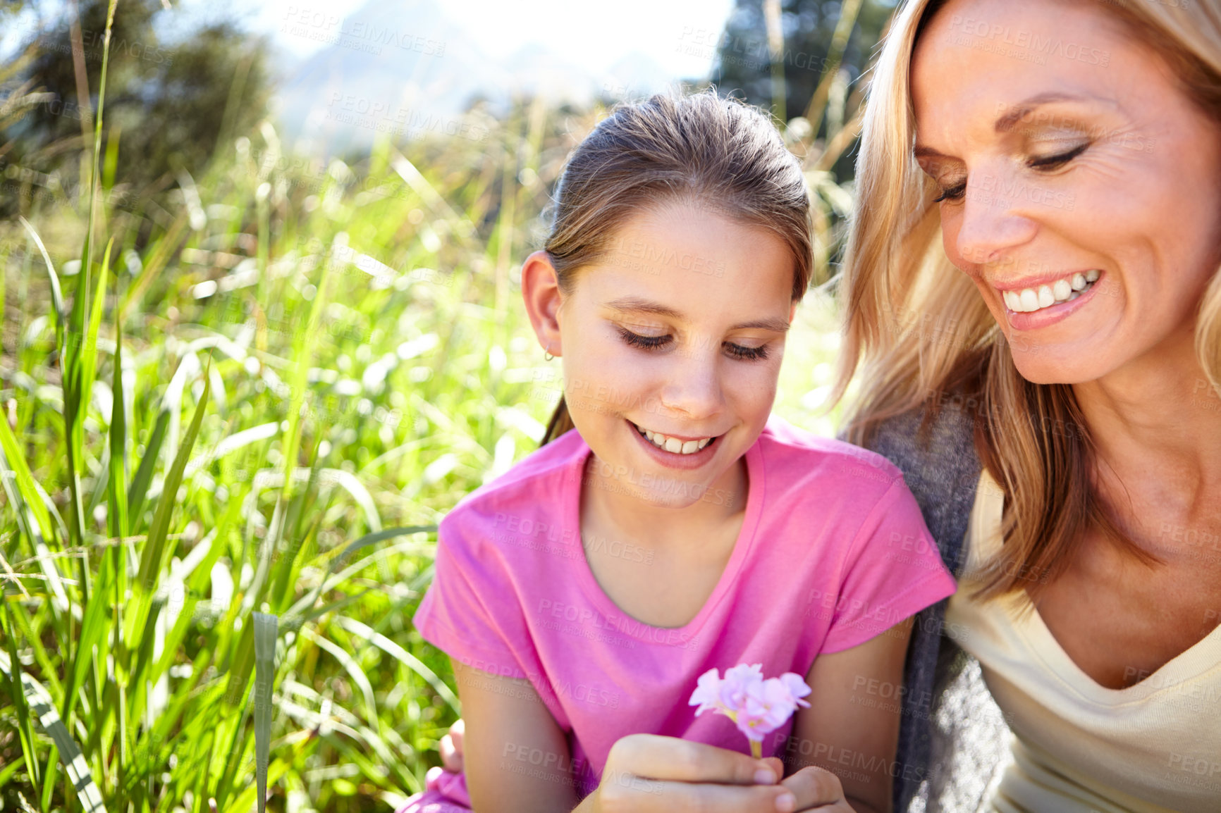 Buy stock photo Smile, girl and mother with flower in nature for childhood development, bonding and relax in field together. Woman, happy and child with plant for vacation, summer holiday or adventure by green grass