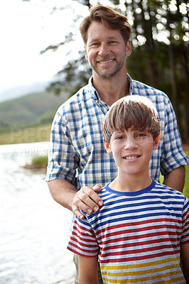 Buy stock photo Portrait of a proud father and his son standing next to a lake