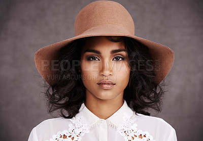 Buy stock photo Cropped portrait of a stylish young woman wearing a hat standing against a gray background