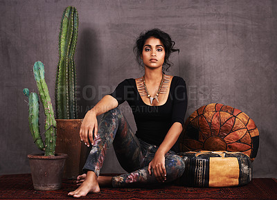 Buy stock photo Studio portrait of a beautiful young woman sitting amongst cacti and cushions