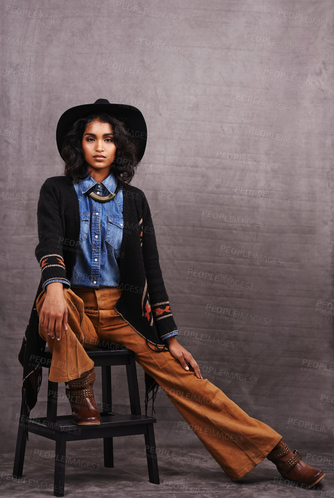 Buy stock photo Portrait, cowgirl or woman in studio, wild west culture and cool fashion in clothing on grey background. Young female person, western lady and stylish model with pride, boho style and chair stool