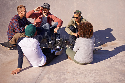 Buy stock photo Shot of a group of friends sitting in the sun at a skate park