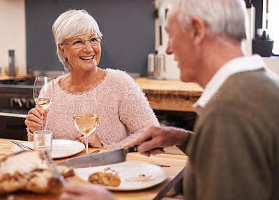 Buy stock photo Elderly couple, food and alcohol for love at table, conversation and healthy meal in home for anniversary. People, bonding and eating together on weekend, relax and speaking on romantic dinner date
