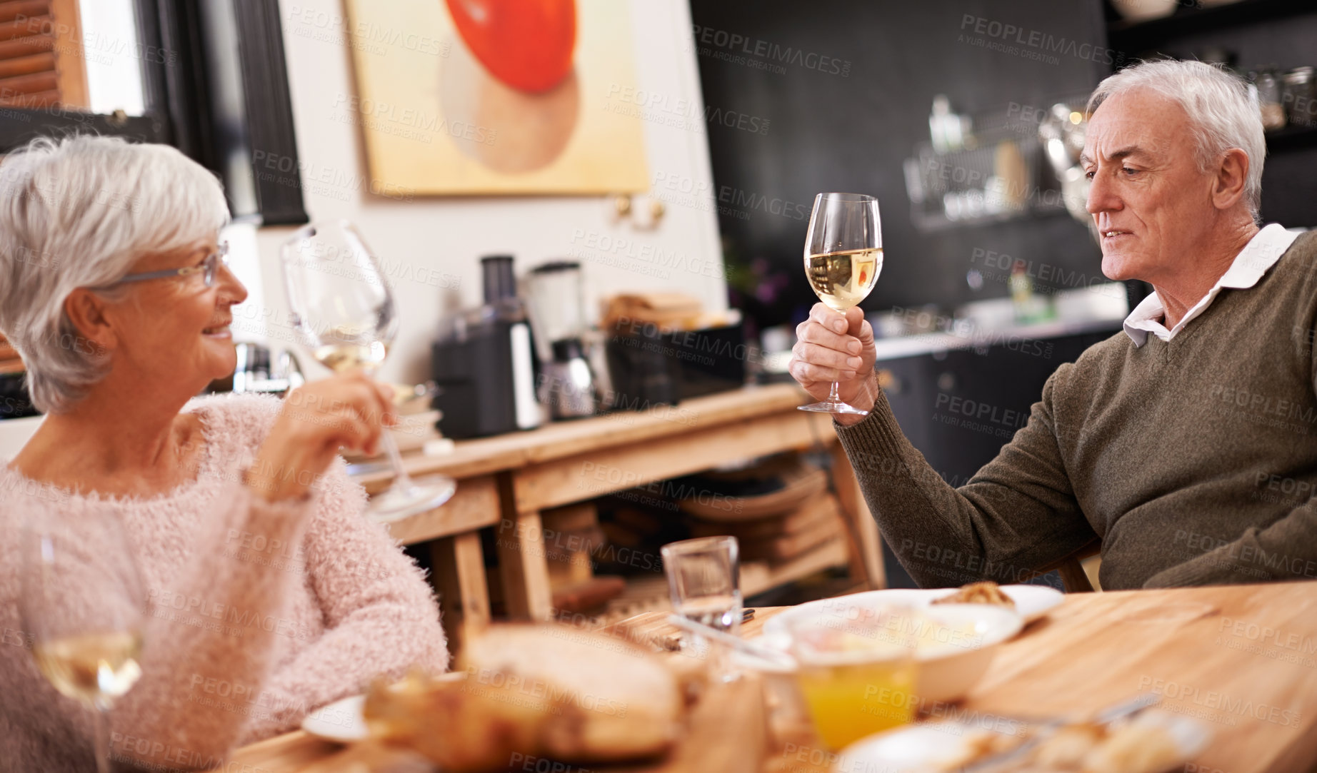 Buy stock photo Senior couple, food and wine for love at table, conversation and healthy meal in home for anniversary. People, bonding and eating together on weekend, alcohol and speaking on romantic dinner date