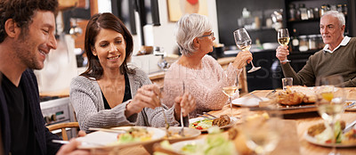 Buy stock photo Cheers, eating and family at dinner in dining room for party, celebration or event at modern home. Smile, bonding and people enjoying meal, supper or lunch together with wine for toast at house.