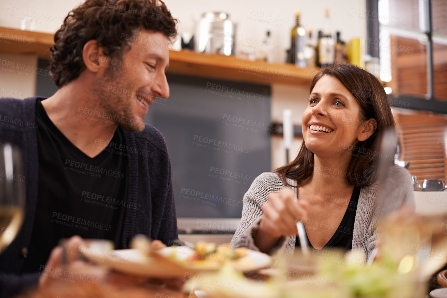Buy stock photo Couple, food and table for love in home, conversation and healthy meal in apartment for anniversary. Happy people, bonding and eating together on weekend, relax and speaking on romantic dinner date