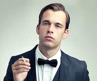 Buy stock photo Portrait, suit or young gentleman smoking a cigarette in studio, confidence or vintage fashion by white background. Face, serious and man in retro clothes or tuxedo, bow tie and class at formal event