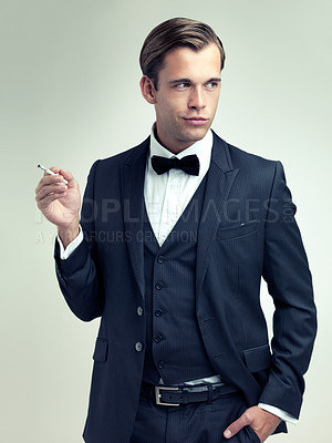 Buy stock photo Elegant, tuxedo or gentleman smoke a cigarette for planning, studio or vintage fashion by white background. Class, confidence or young man for thinking in retro suit, bow tie or idea in formal style