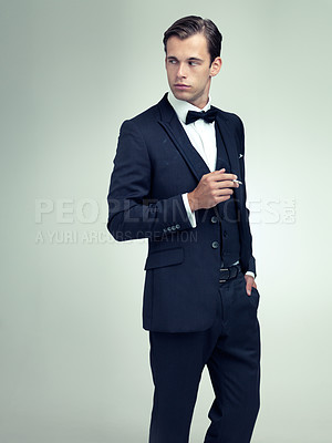 Buy stock photo Thinking, elegant or young gentleman smoking a cigarette in studio, confidence or vintage fashion by white background. Serious, man and idea in retro suit or tuxedo, bow tie and class at formal event