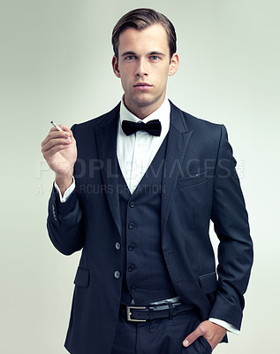 Buy stock photo A studio portrait of a confident young gentleman smoking a cigarette