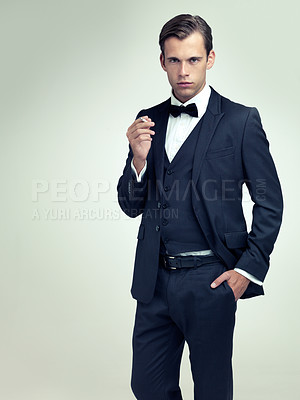 Buy stock photo Portrait, serious or young gentleman smoke a cigarette in studio, confidence or vintage fashion by white background. Face, tobacco or man in retro suit or tuxedo, bowtie or hands in pocket for class